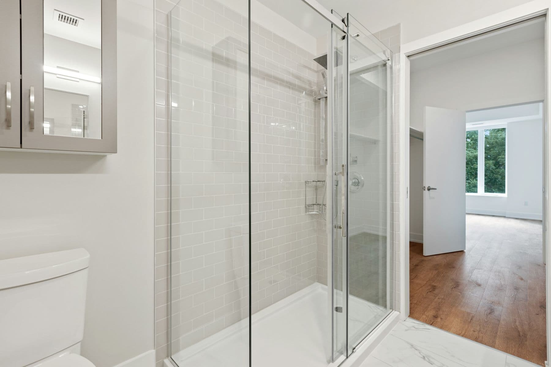 Walk-in shower with a sliding glass door and light tile
