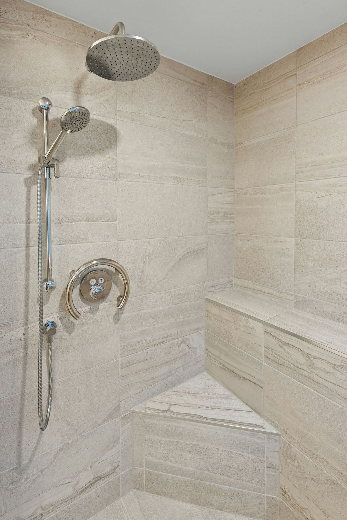 Tiled walk-in shower with a tiled floor, handheld shower and tiled bench